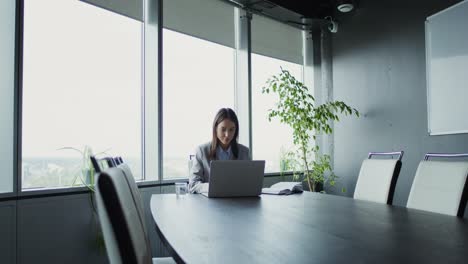 businesswoman working on laptop in a modern conference room