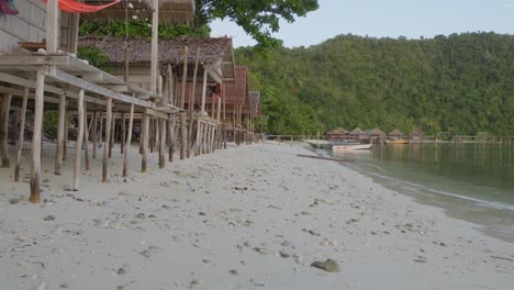 Holzhütten-Am-Sandstrand-Der-Insel-Kri-Im-Raja-Ampat-Archipel-In-Indonesien,-Getrübt-Durch-Den-Unglücklichen-Anblick-Zweier-Plastikflaschen,-Die-Die-Unberührte-Landschaft-Verunreinigen