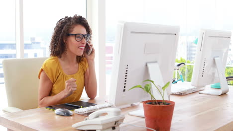 una mujer de negocios emocionada hablando por teléfono.