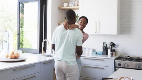 Una-Pareja-Diversa-Comparte-Un-Cálido-Abrazo-Y-Bailan-Juntos-En-Una-Cocina-Moderna