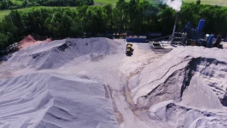 work bulldozer among the embankments of rubble and sand in the territory of an asphalt plant
