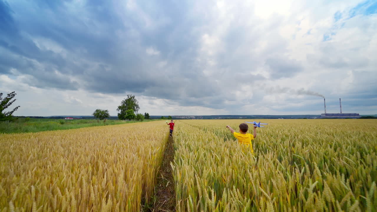 Children having fun on agricultural field. Boys launching toy planes in farmland in summer day. Happy childhood.
