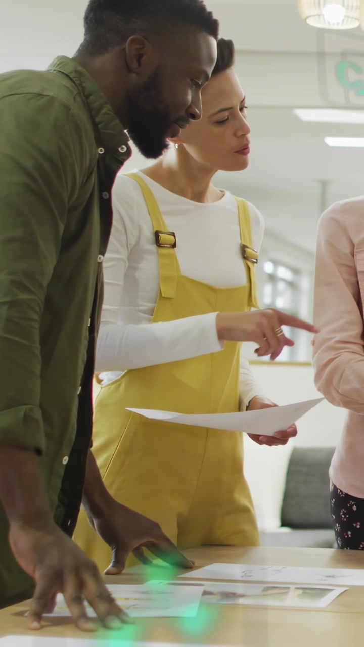 Video verticale: Donna che porge un foglio e uomo che si china a controllare i design, con un'overlay verde che guida le scelte