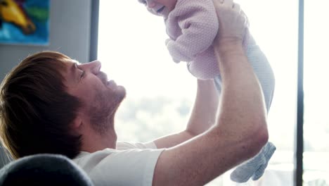 cheerful dad holding happy baby daughter