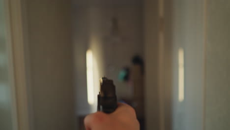 first-person view of a person cautiously moving through a corridor with a handgun, filmed with a hand-held camera