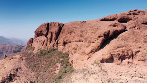 Luftbild-Drohnenverfolgung-über-Trockenen-Roten-Felsrücken-In-Richtung-Bergtal-Auf-Gran-Canaria,-Spanien