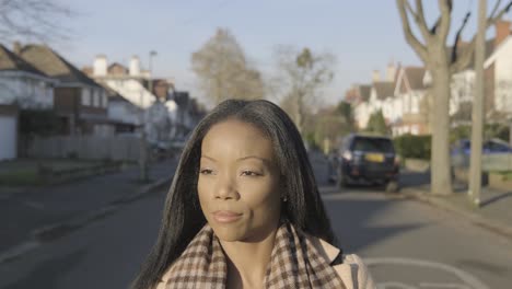 confident black businesswoman walking on street road with sunlight on face in central london