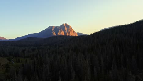 aerial drone landscape nature shot rising above pine trees to reveal the beautiful red castle lake mountain up in the high uinta's between utah and wyoming on a backpacking trip during a summer sunset