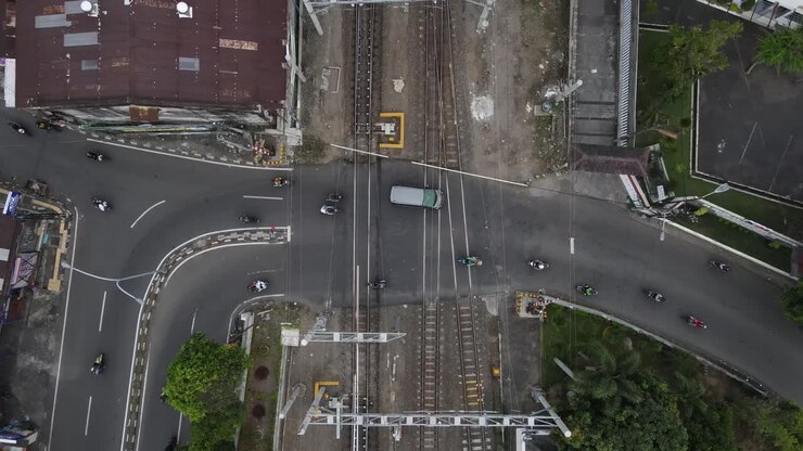 aerial view, smooth traffic of motorbikes and cars passing the railroad crossing near Lempuyangan station, yogyakarta