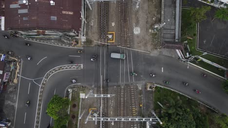 aerial-view,-smooth-traffic-of-motorbikes-and-cars-passing-the-railroad-crossing-near-Lempuyangan-station,-yogyakarta