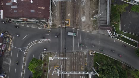 aerial view, smooth traffic of motorbikes and cars passing the railroad crossing near lempuyangan station, yogyakarta