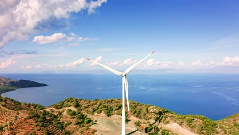 Aerial-view-of-Turkish-Mediterranean-coastline-with-rotating-wind-power-generators-on-the-mountain-ridge,-Muğla-province,-Reşadiye-peninsula