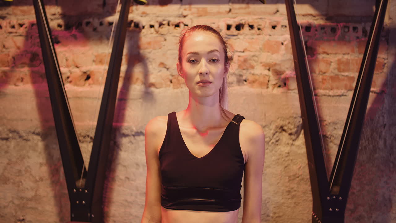 Fast billedindstilling af smuk, selvsikker ung kvinde, der står i en fitnessklub