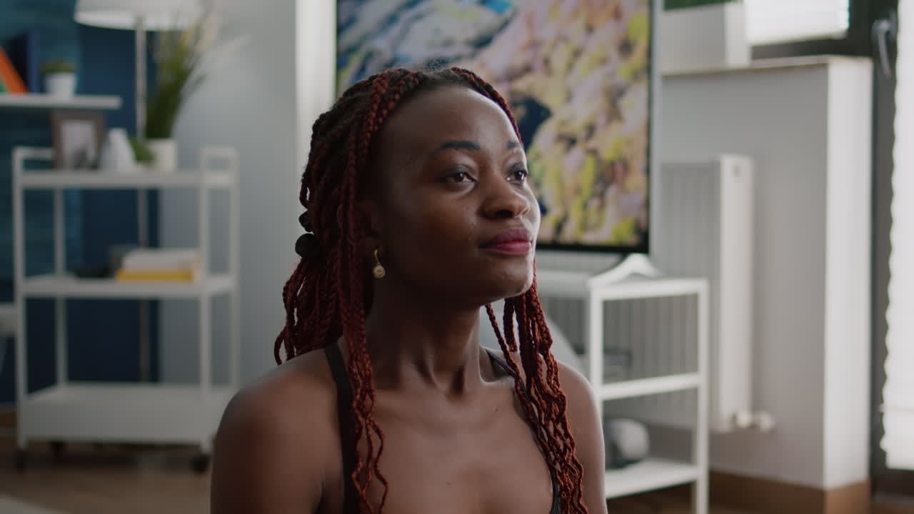 검은 피부를 가진 탄력적인 여성이 호흡 운동을 연습하고 있습니다.