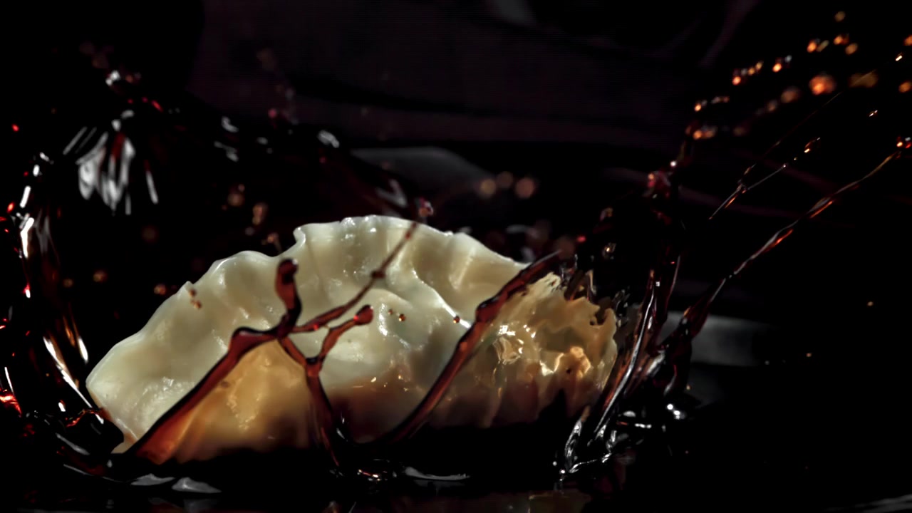 Ravioli tombant dans de la sauce soja avec une éclaboussure spectaculaire au ralenti