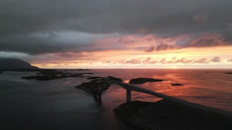 flying over the atlantic ocean road in norway at sunset with the architectural masterpiece bridge surrounded by the ocean and cars crossing the islands