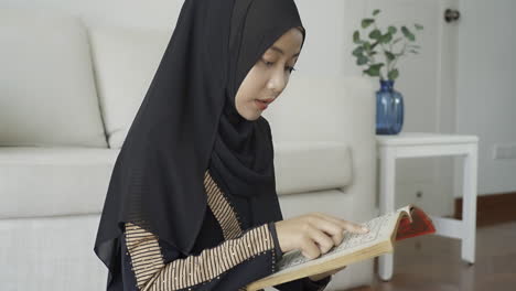 an asian muslim woman reciting salah or salat al-fatiha passage of the qur'an, in a single act of sujud called a sajdah or prostrations at home