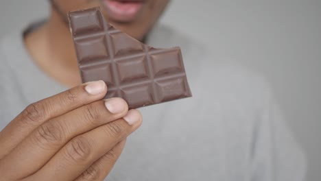 person holding and eating a piece of dark chocolate