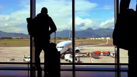 mochilero mira por la ventana de la zona de salidas del aeropuerto