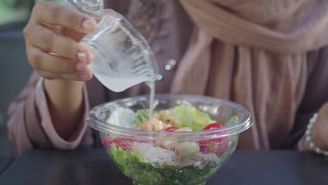 woman pouring dressing on a salad