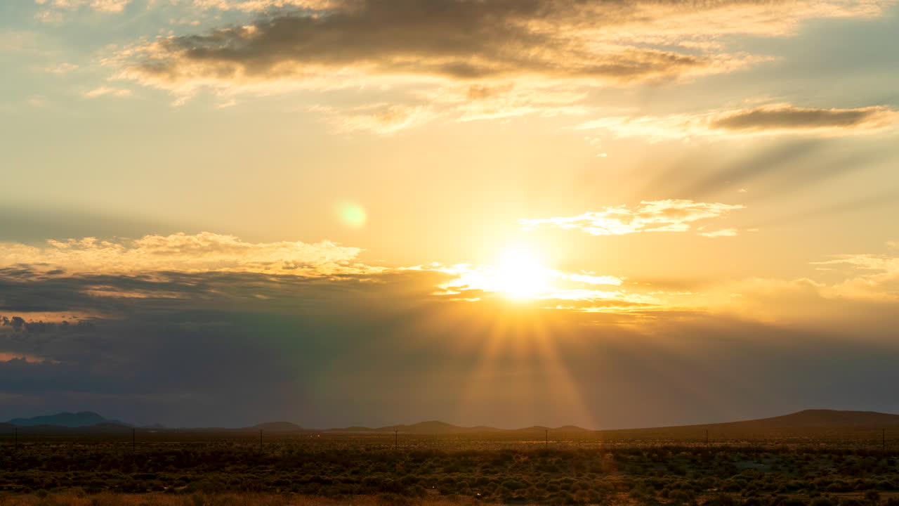 los rayos del sol perforan las nubes mientras el amanecer ilumina el paisaje del desierto de mojave - lapso de tiempo estático