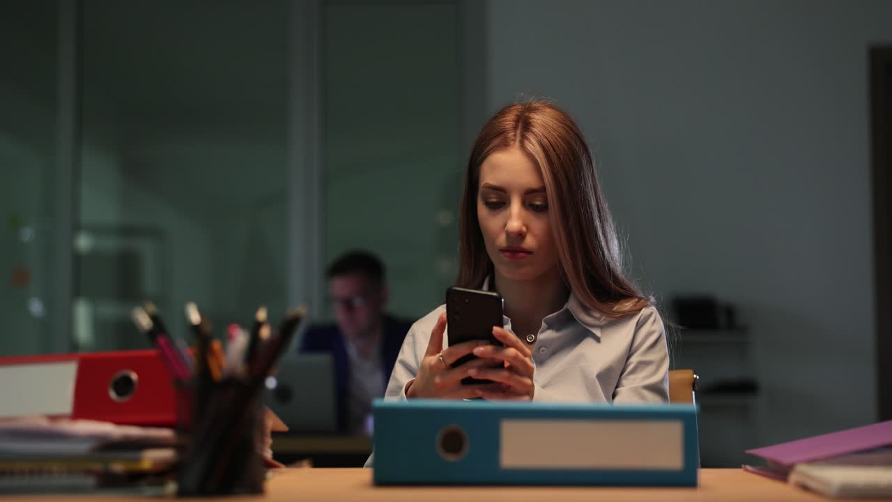 Young woman using smartphone at an office desk