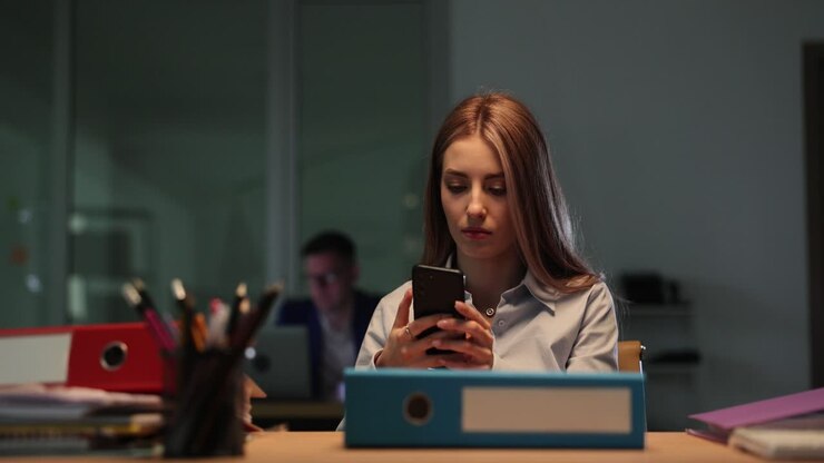 Young woman using smartphone at an office desk