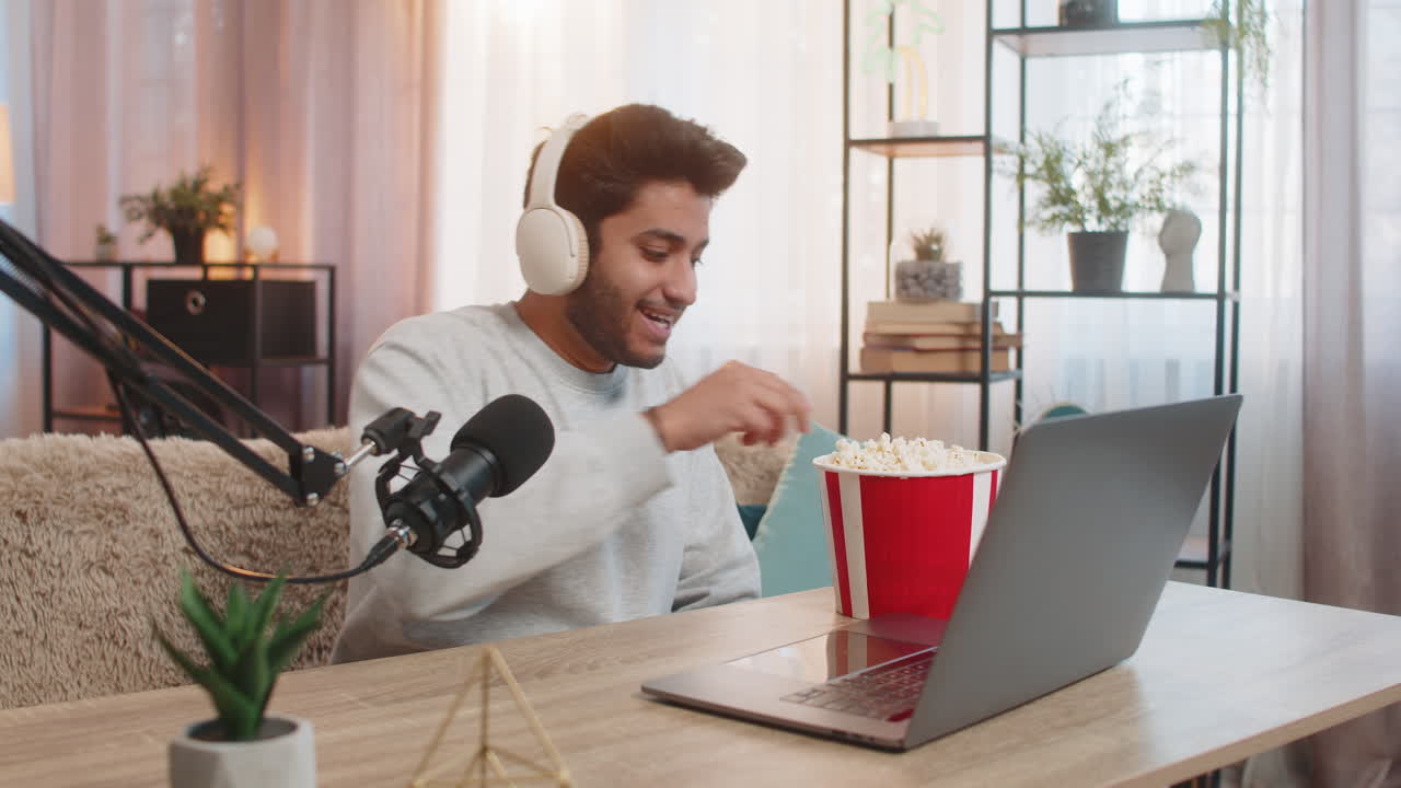 joven indio transmitiendo comentarios de partidos de fútbol comiendo palomitas de maíz y involucrando a la audiencia en casa