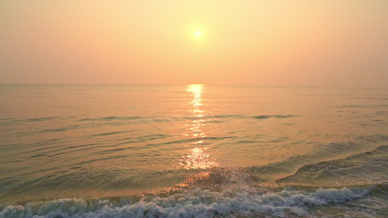 Slow-motion of the tide coming in under a tropical pink and orange sunset