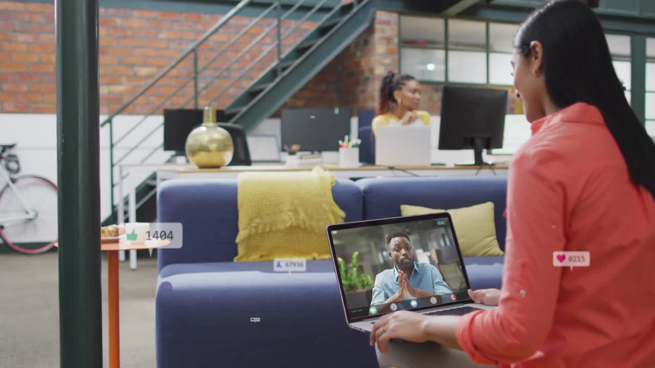 Woman holding laptop watching remote host gesturing, badges rising around her during business call