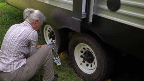 closeup of elderly woman unscrewing a tire locking chock on an rv