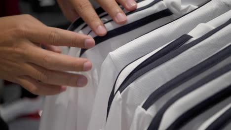 Faceless-man-looking-for-his-shirt-size-in-a-store-while-shopping-clothes,-hands-close-up