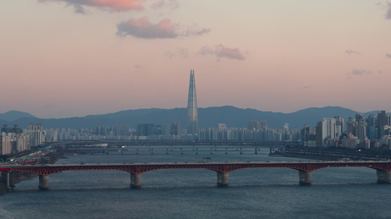 Vista aerea del ponte Seongsu di color arancio-rossastro e della Lotte World Tower durante un vivace tramonto rosa in inverno a Seoul