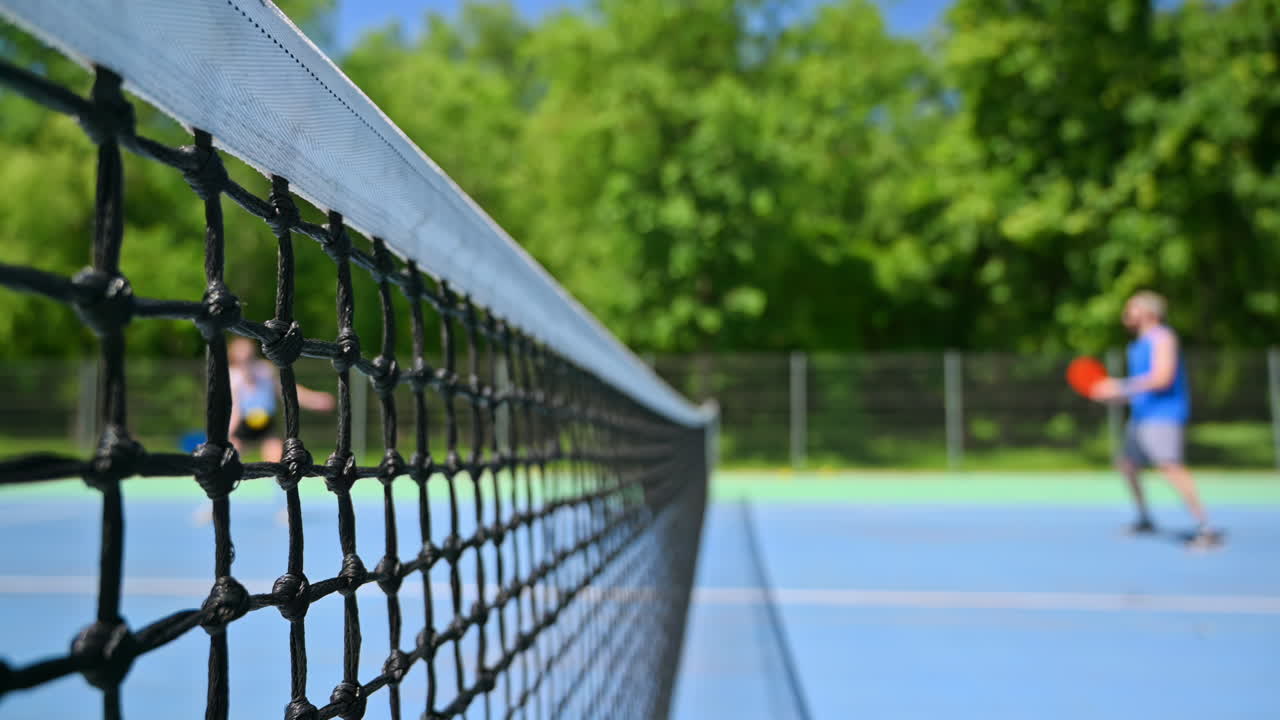A man and a woman playing pickleball on a sunny day