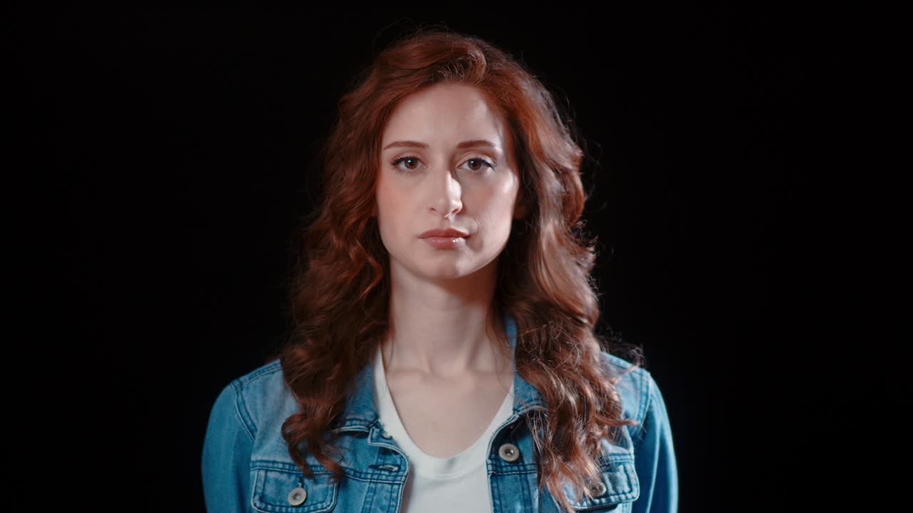 Una giovane donna caucasica si volta a guardare la telecamera con un'espressione seria.