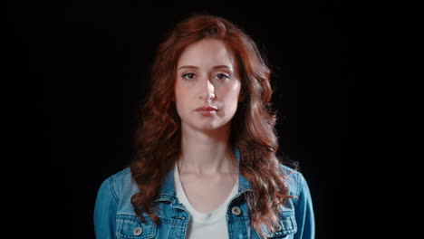 a young caucasian woman turns to look at the camera with a serious expression