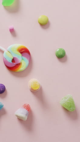 video of colourful various sweets on pink background