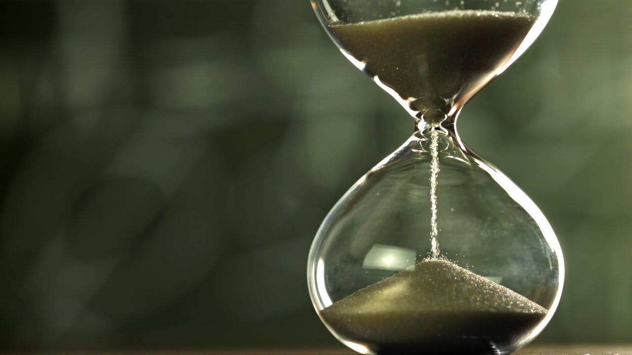 Close-up of Sand Falling in a Glass Hourglass