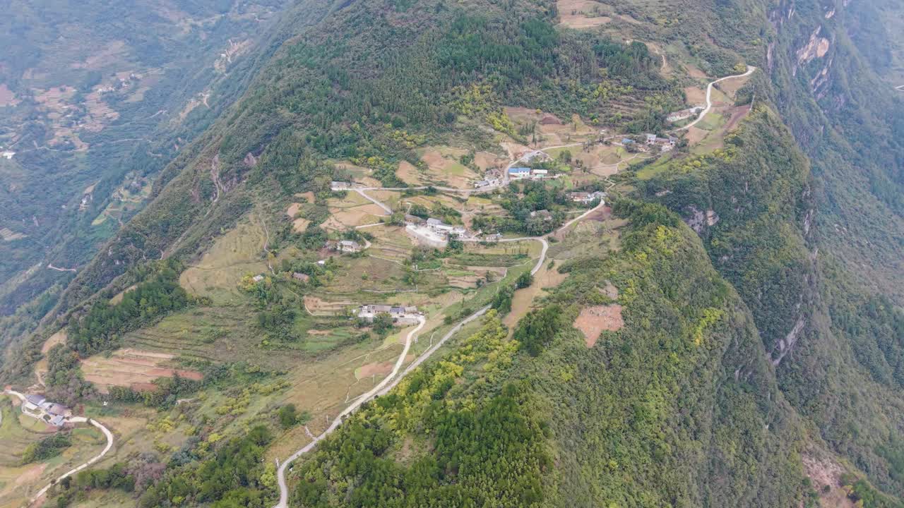 Aerial view of Linpaishi Minzhu Village perched on steep mountain slopes in Wuxi County, showcasing winding rural roads, terraced fields, scattered homes, and lush green highland scenery