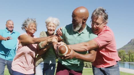 Happy-senior-diverse-people-playing-rugby-in-garden-at-retirement-home