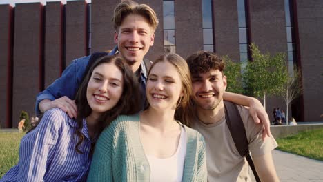 Portrait-of-four-caucasian-university-students-sitting-outside-the-university-campus