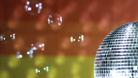 bola de discoteca brillante girando con burbujas flotantes contra la bandera del arco iris