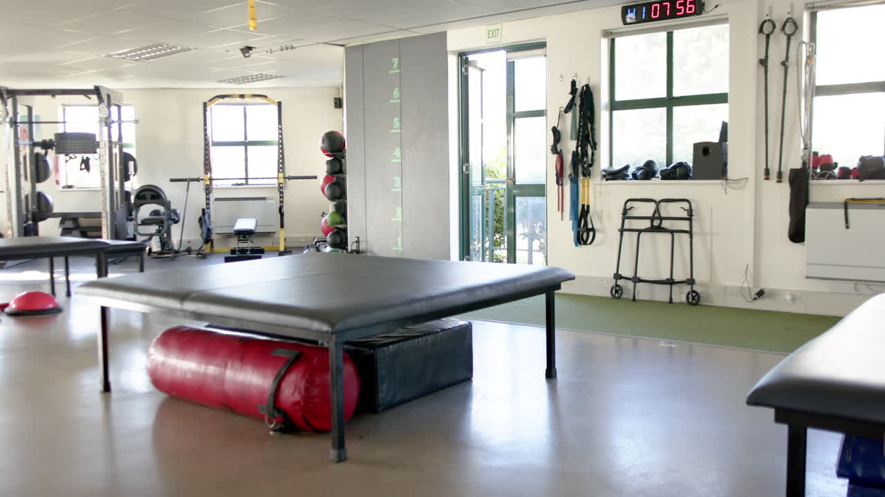 Rehabilitation center with exercise equipment, therapy table, and mobility aids, copy space