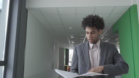profesor afroamericano hojeando un cuaderno y sonriendo.