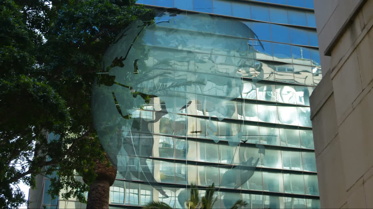 Modern glass facade displaying world map overlay, reflecting sky and building shapes near palm tree