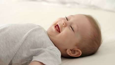 loving mother tickling her baby girl on the bed