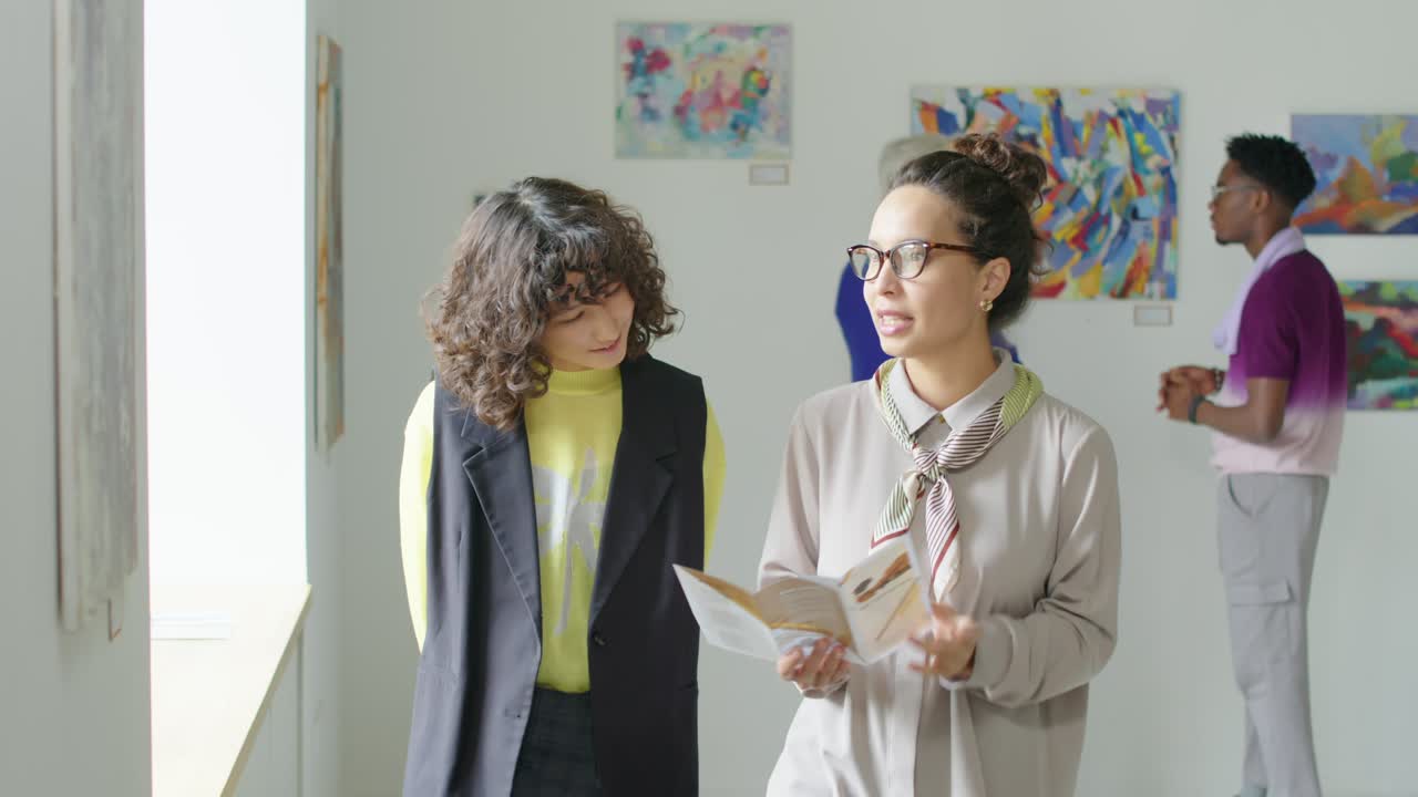 Gallery Guide Telling Female Visitor about Artworks