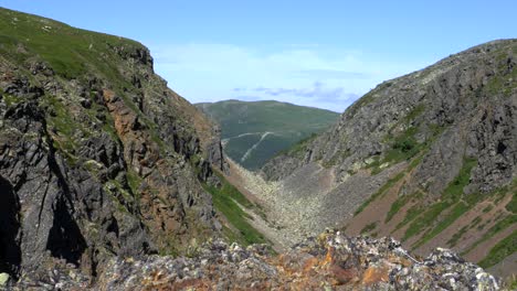 Zoom-in-shot-of-a-split-mountain-barren-rocky-landscape-of-dried-up-river-canyon-during-summer-at-Bydalen-in-Jamtland,-Sweden