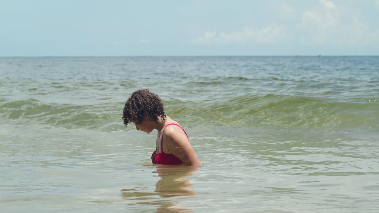 imagina una playa de arena blanca bañada en la luz del sol, con una chica en su juventud en un bikini