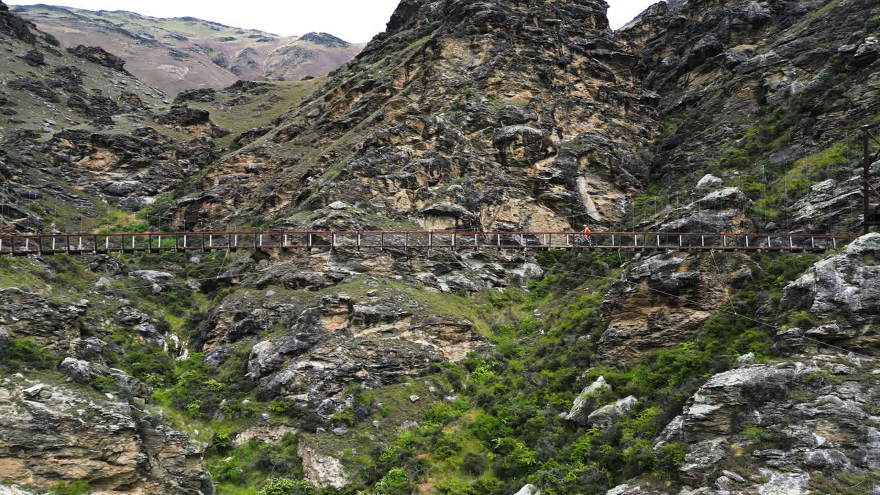 뉴질랜드 계곡 위의 흔들다리에서 자전거 타기